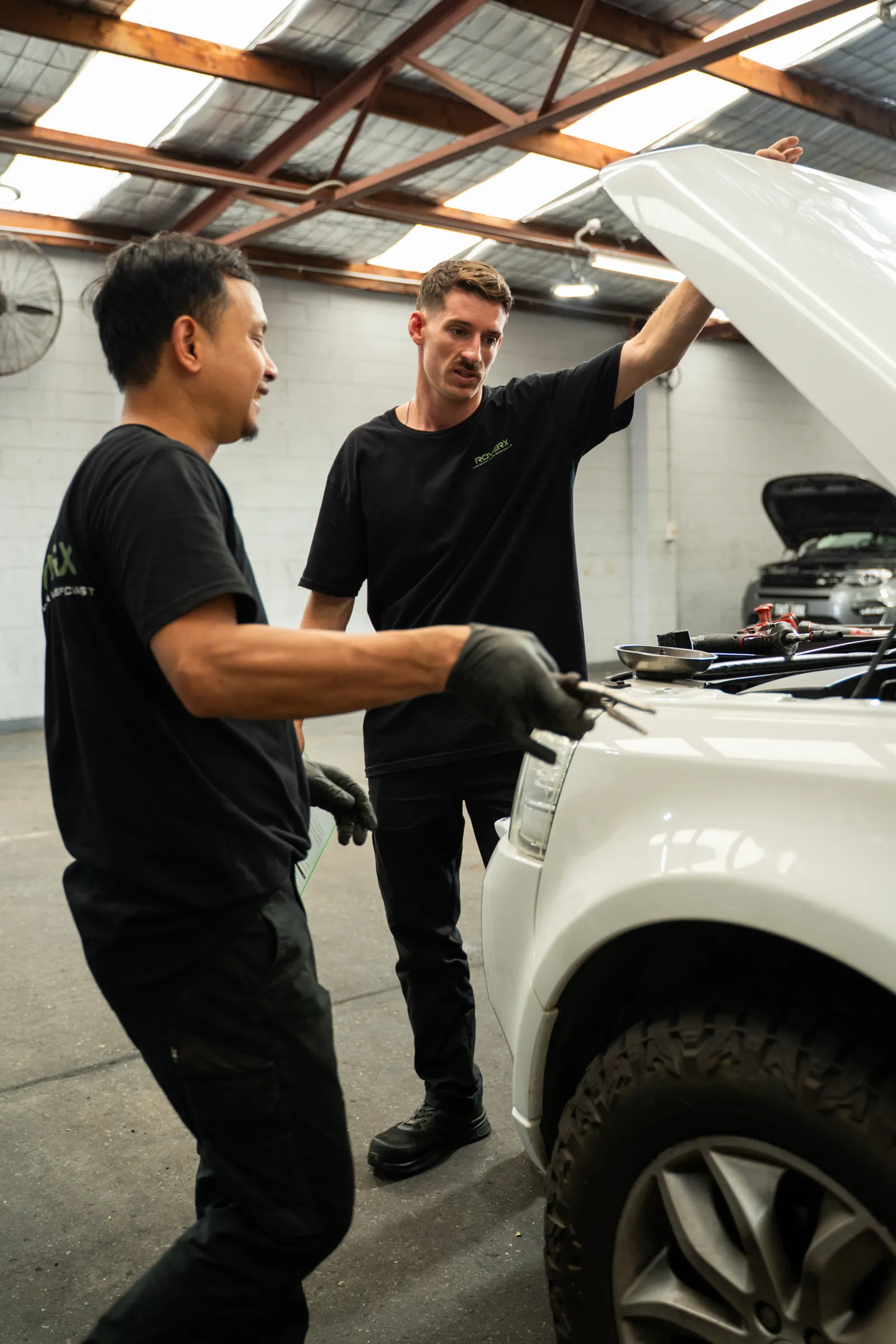 RoverX technicians inspecting a white Range Rover in the workshop