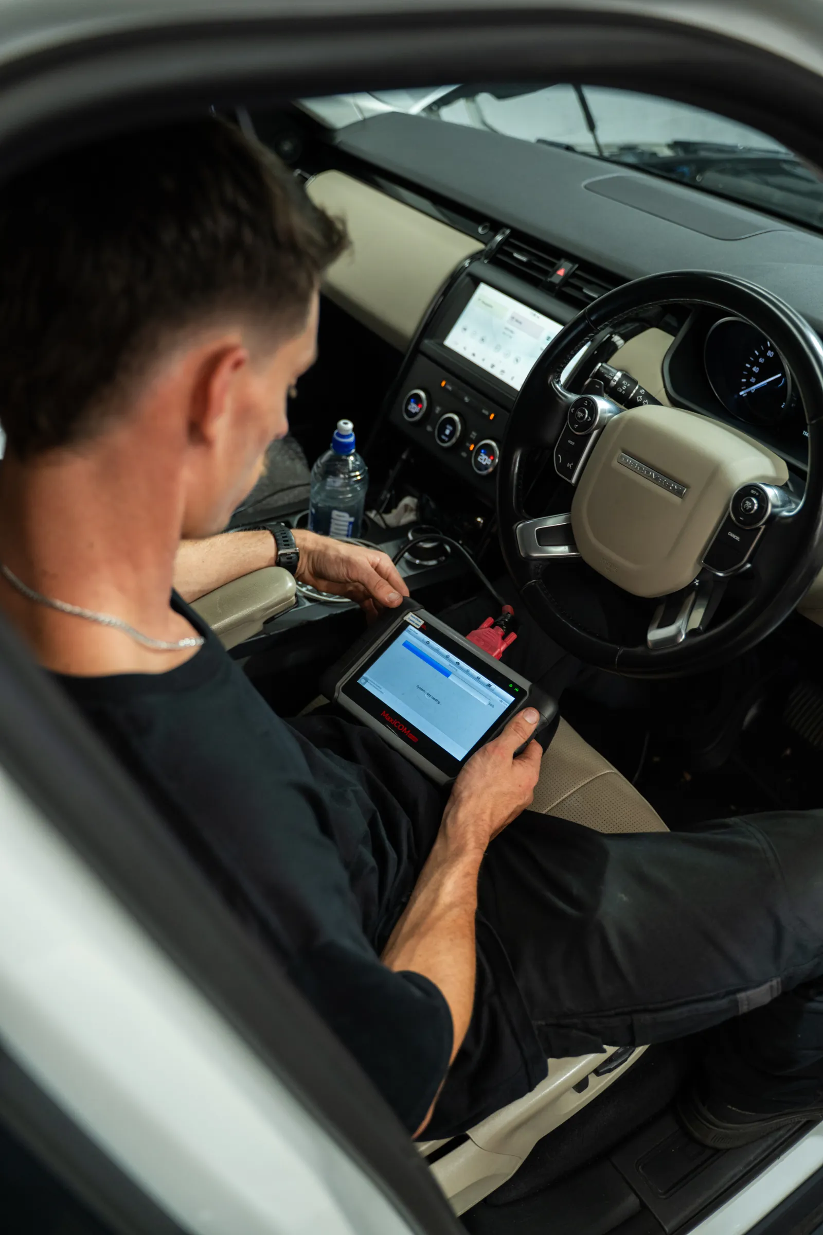 RoverX technician running JLR diagnostics on a tablet inside a Range Rover